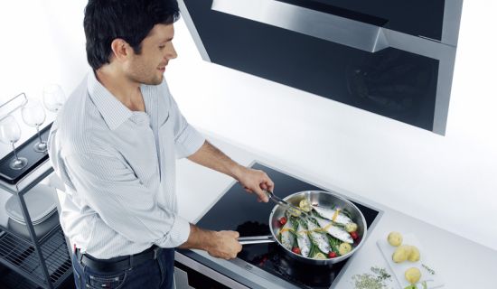 Mann brät Fisch auf dem Herd