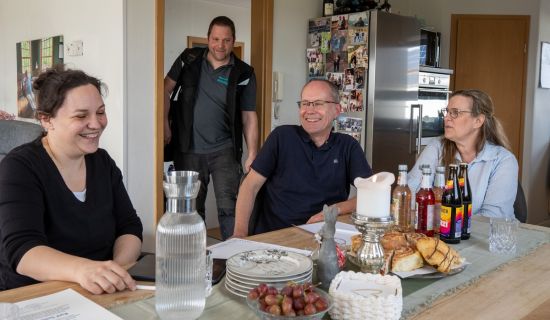 Familie Schmidt am Esstisch mit der Energieberaterin und dem Handwerker
