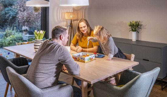 Eine Familie spielt am Esstisch ein Gesellschaftsspiel