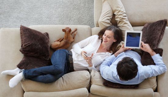 Paar auf Couch, er surft im Internet