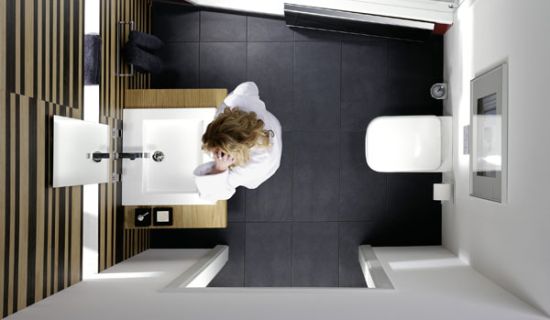 Blick von oben in ein kleines Bad: Eine Frau steht vorm Waschbecken