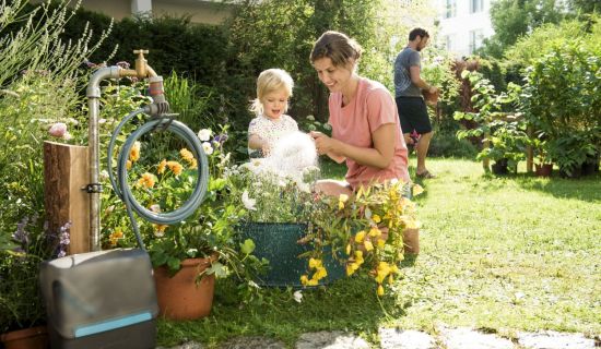 Frau und Kind wässern die Pflanzen