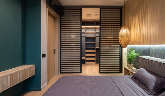 Ein Schlafzimmer, das mittels einer Schiebetür vom Ankleideraum dahinter getrennt ist