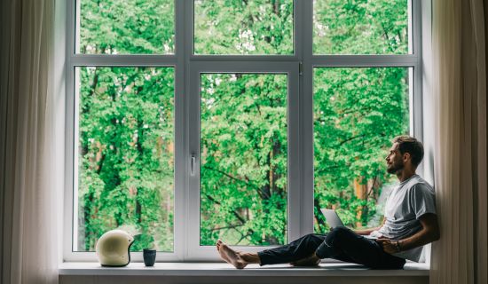 Mann blickt aus Fenster ins Grüne