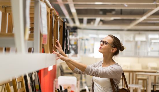 Frau vergleicht Holzmöbel im Geschäft