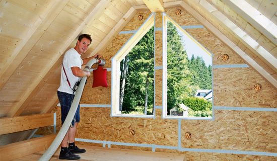 Die Holzfasern werden zwischen den Dachbalken eingeblasen