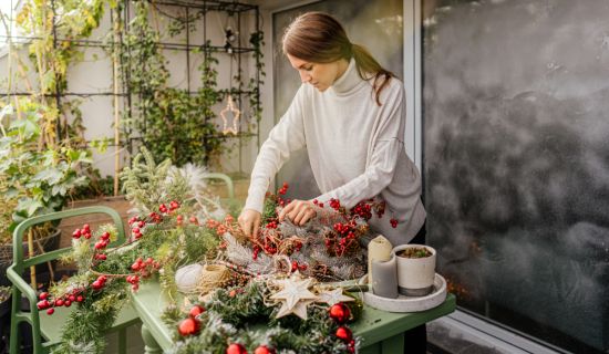 Frau gestaltet Balkon im Winter mit Pflanzen