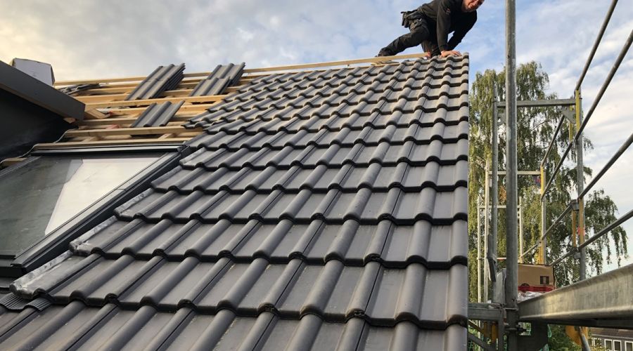 Dach mit neuer Dacheindeckung, die letzten zu verbauenden Ziegel liegt noch links auf dem Dach.