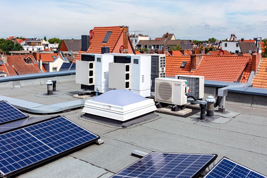 Außenmodule der Wärmepumpe stehen auf dem Dach eines Mehrfamilienhauses.