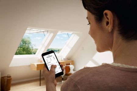 Frau öffnet die Dachfenster per App