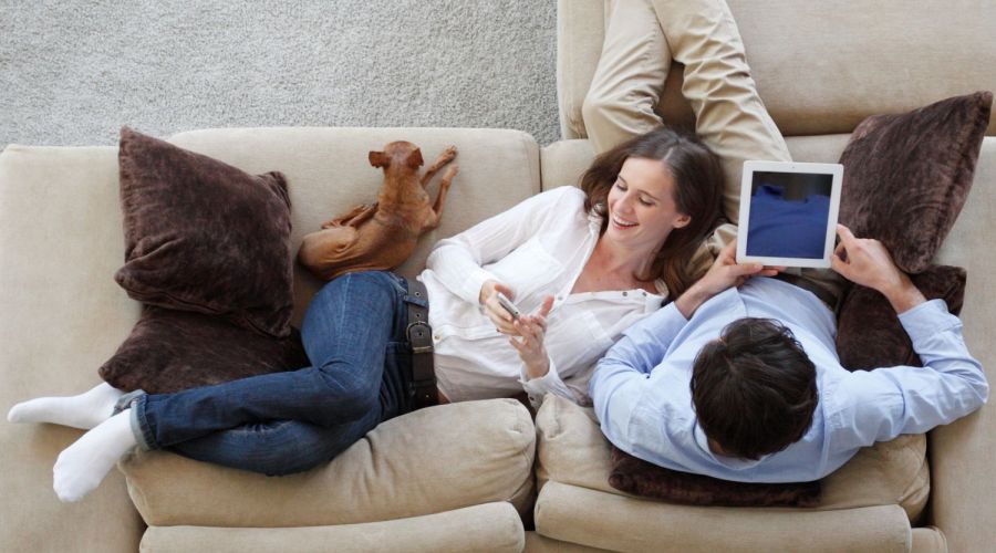 Paar auf Couch, er surft im Internet