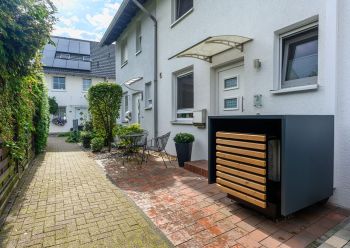 Gut schallgeschützte Luft-Wärmepumpe vor einem Reihenhaus