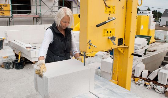 Frau trägt Ytong-Baustein auf Baustelle