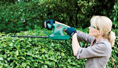 Frau beim Hecke schneiden