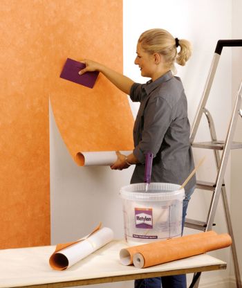 Frau tapeziert eine Wand