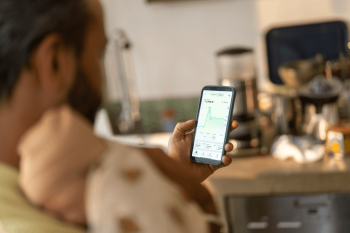 Mann sitzt im Sessel und checkt seinen Stromverbrauch am Smartphone