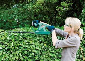 Frau beim Hecke schneiden