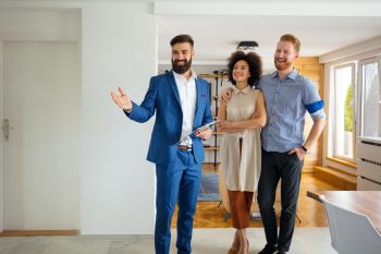 Makler zeigt einem Paar eine Wohnung bei einer Immobilienbesichtigung.