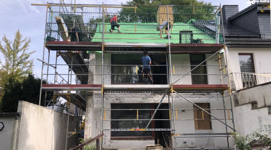 Eingerüstetes Haus mit Dachdeckern in Aktion