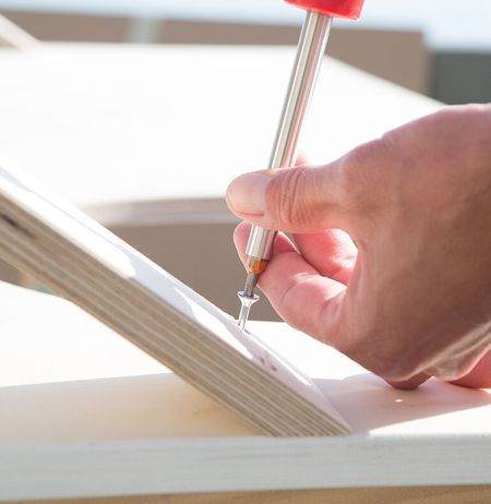 Hand verschraubt Schraube im Holz