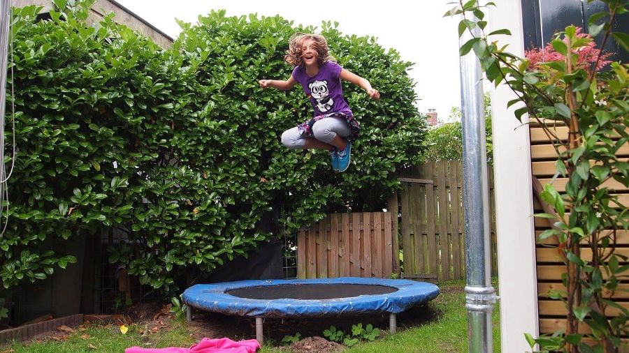 Kind springt im Garten auf Trampolin