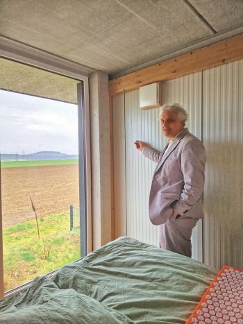 Architekt Florian Stocker steht vor einem deckenhohen Fenster