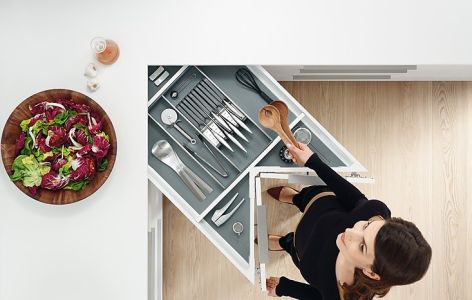 Frau öffnet Besteckschublade in Eckschrank