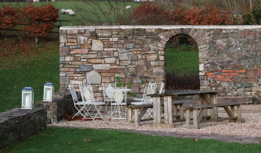 Angelegte Terrasse aus Kies, dahinter ist eine Natursteinmauer