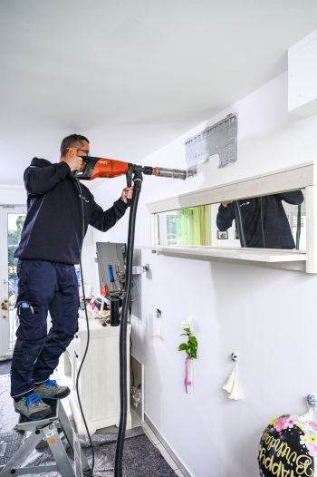 Mann bohrt in die Wand