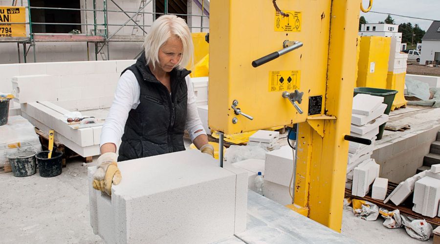 Frau trägt Ytong-Baustein auf Baustelle