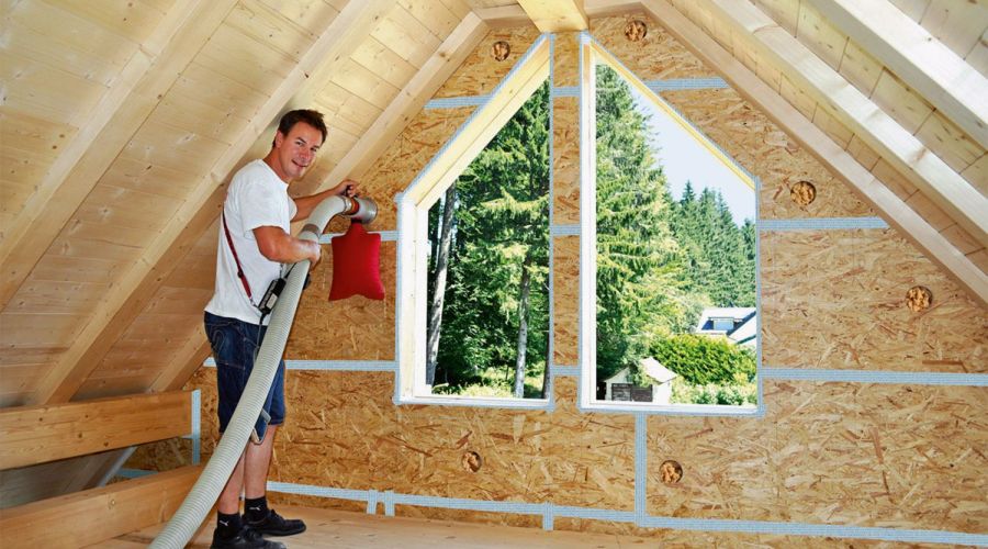 Die Holzfasern werden zwischen den Dachbalken eingeblasen