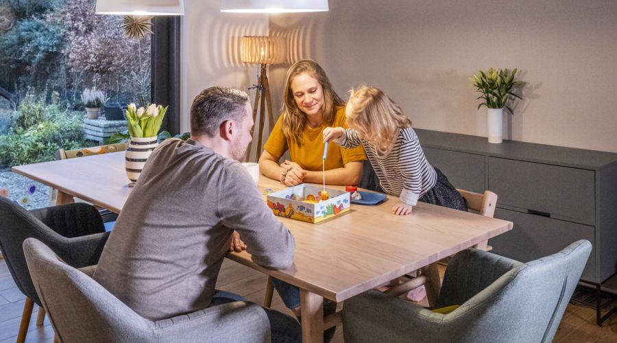 Eine Familie spielt am Esstisch ein Gesellschaftsspiel