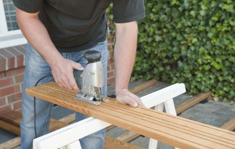 Mann sägt Terrassendiele längs durch
