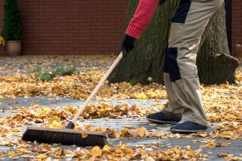 Mann fegt Herbstlaub zusammen