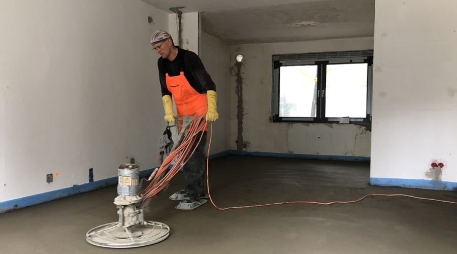 Handwerker schleift den Estrich.