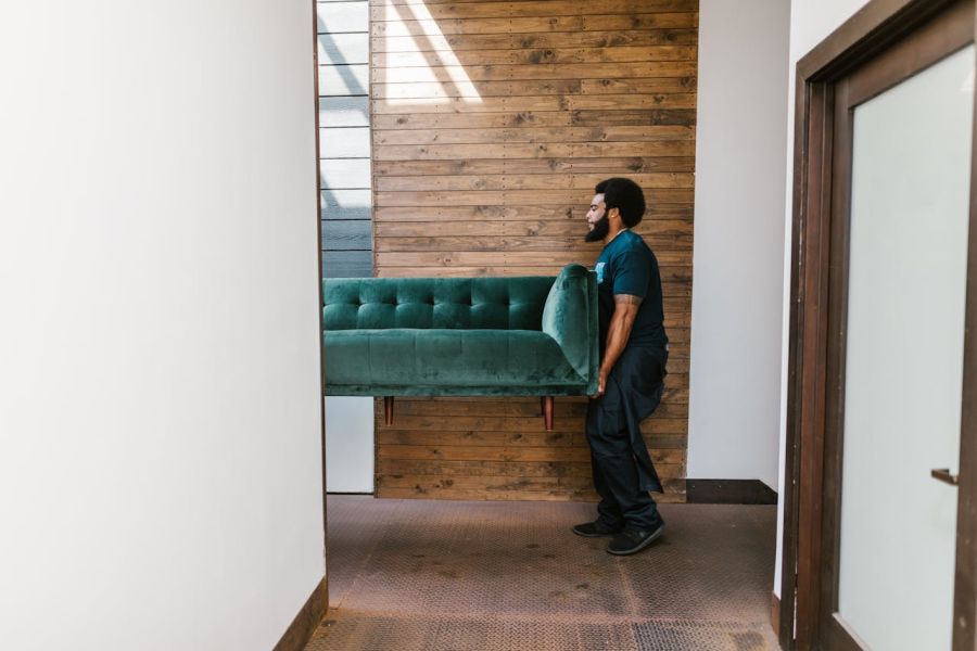Ein Mann trägt ein Sofa aus der Wohnung