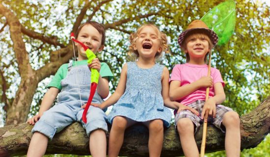 Kinder sitzen auf dickem Ast