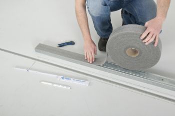 Mann bringt Dämmstreifen an Bodenschiene an