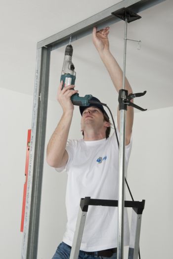 Mann fixiert Deckenschiene an der Decke