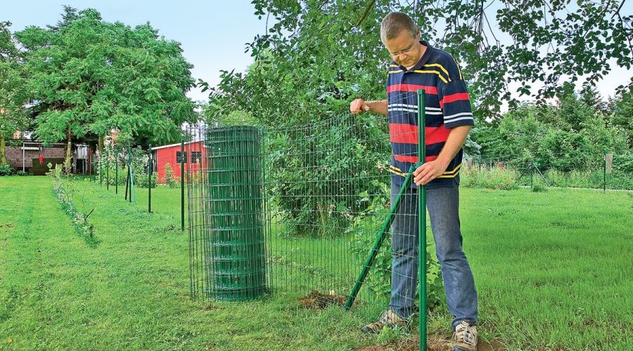 Gitterzaun wird am Gerüst ausgerollt