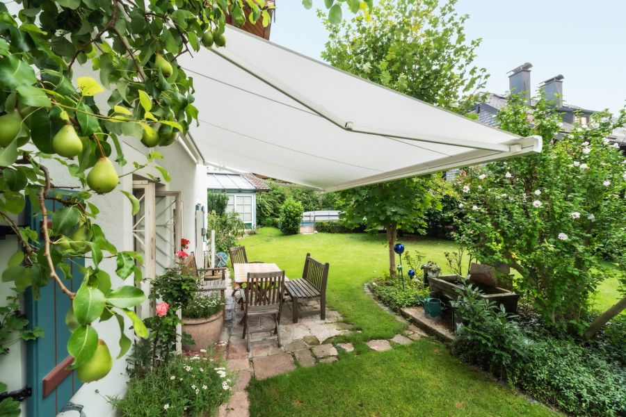Terrasse aus Natursteinen, darüber ist eine weiße Markise gespannt