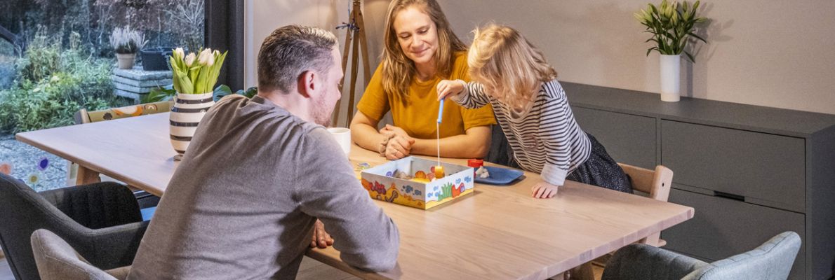 Eine Familie spielt am Esstisch ein Gesellschaftsspiel