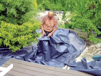 Mann verlegt Folie für einen Teich