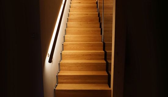 Offene Holztreppe mit indirekter Beleuchtung entlang der Treppenstufen