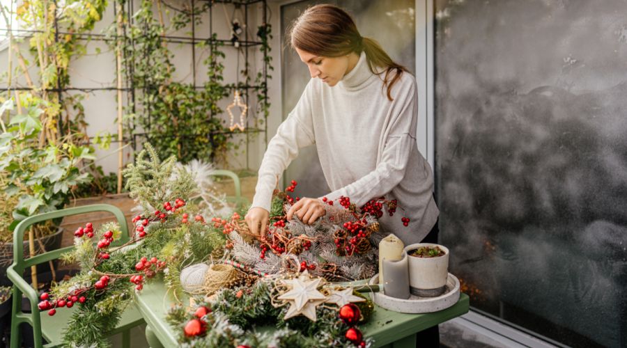 Frau gestaltet Balkon im Winter mit Pflanzen