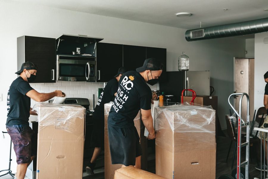 Mehrere Männer packen Umzugskartons auf Rollwägen ein und verpacken sie professionell