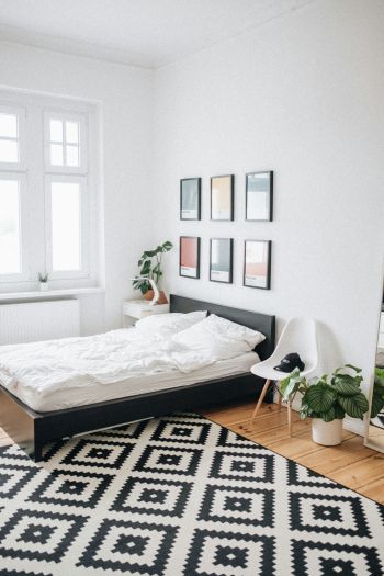Ein einfaches, aber modernes, schwarzes Bett in einem noch spartanisch eingerichtetem Zimmer.