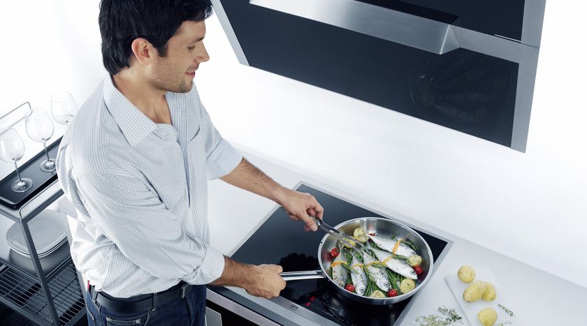 Mann brät Fisch auf dem Herd
