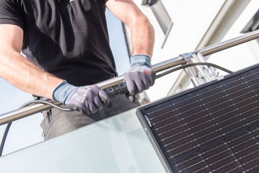Mann steckt Kabel an Solaranlage zusammen