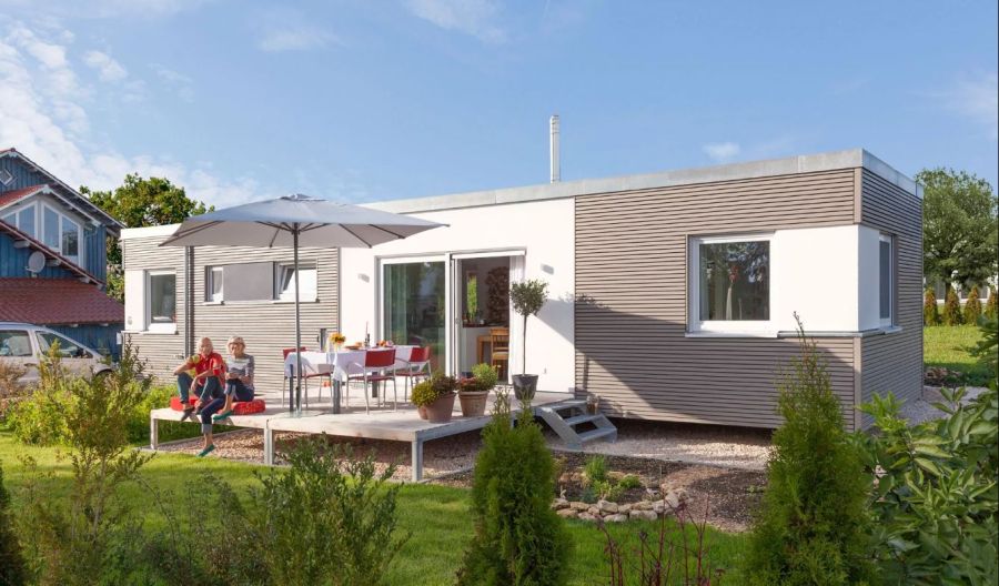 Ehepaar sitzt im Grünen, auf der Terrasse vor ihrem Minihaus